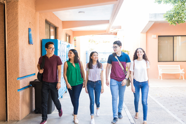 Täyspitkä teini-ikäiset opiskelijat kävelevät yhdessä käytävällä lukiossa
 - Valokuva, kuva