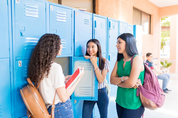 Teen κορίτσια μιλούν ενώ στέκονται στο διάδρομο στο Πανεπιστήμιο - Φωτογραφία, εικόνα