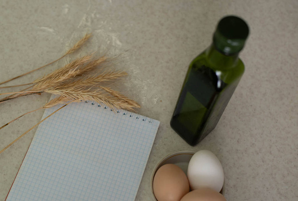 Blocco note, olio e uova in tavola
 - Foto, immagini
