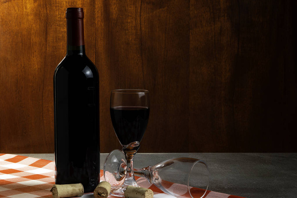 Ένα μπουκάλι κόκκινο κρασί στο κελάρι για γευσιγνωσία κρασιού. Κόκκινο ξύλινο φόντο. Ελληνική παράδοση και κουλτούρα. - Φωτογραφία, εικόνα