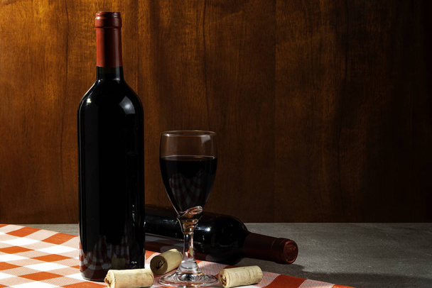 Bottle of red wine in wine cellar for tasting. Red wood background. Wine tradition and culture concept. - Photo, Image