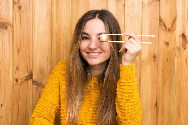 Young woman with sushi over wood background - Foto, Imagen