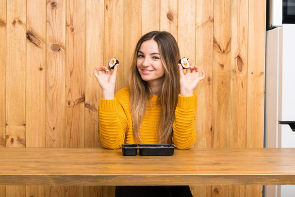 Νεαρή γυναίκα με σούσι πάνω από ξύλο φόντο - Φωτογραφία, εικόνα