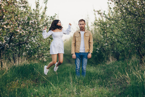 Молодий чоловік і дівчина гуляють в парку на заході сонця, проти емоцій сум і щастя
 - Фото, зображення