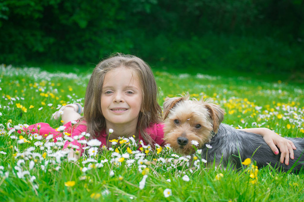 Ένα ευτυχισμένο κοριτσάκι με το σκύλο της στο πάρκο..  - Φωτογραφία, εικόνα