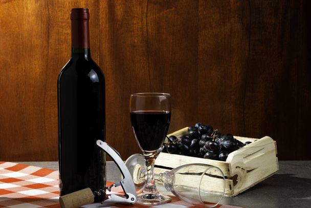 Üveg vörösbor borospincében a kóstolás. Piros fa háttér fadobozban szőlő. A borhagyomány és a kultúra fogalma. - Fotó, kép
