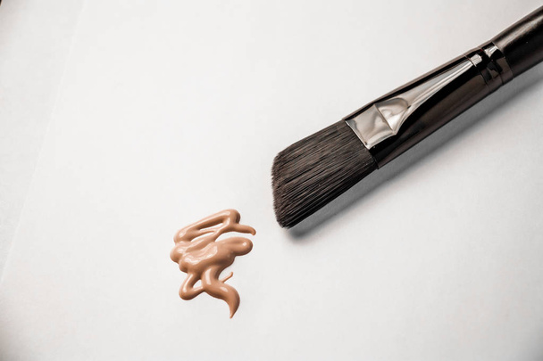 smear of foundation and black makeup brush - Foto, afbeelding