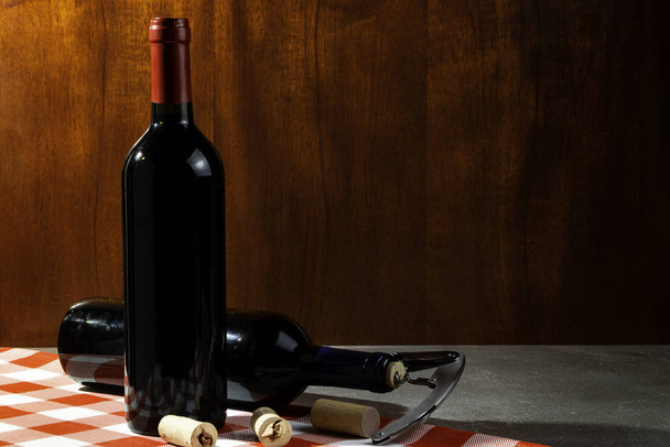 Botella de vino tinto en bodega para degustación. Fondo de madera roja. Concepto de tradición y cultura del vino
. - Foto, imagen