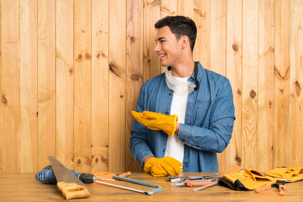 Craftsmen man over wood background extending hands to the side for inviting to come - Photo, Image