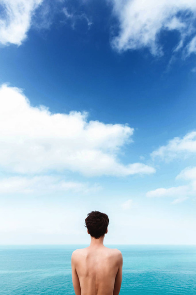 slim girl with a beautiful bare back is standing on the sea. Blue sky with clouds. Unity with nature. freedom. Life - Photo, Image