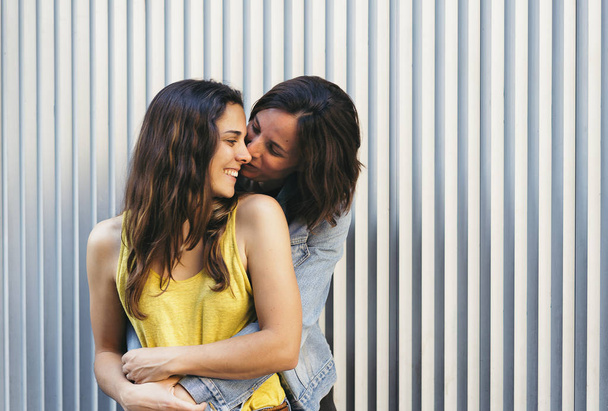 Прихильна жінка цілує свою щасливу дівчину посміхаючись, концепція однакових сексуальних відносин
. - Фото, зображення