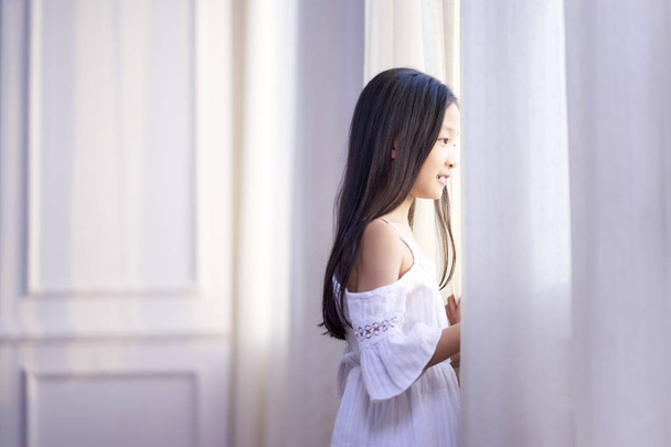 маленька азіатська дівчинка дивиться з вікна
 - Фото, зображення