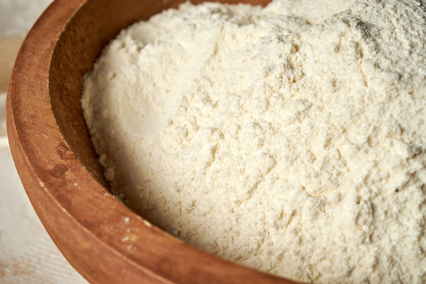 Zbliżenie mąki w drewnianej misce na białym stole. - Zdjęcie, obraz