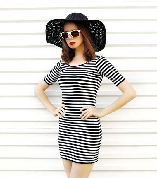 Stylish young woman in striped dress, summer straw hat posing on - Foto, afbeelding