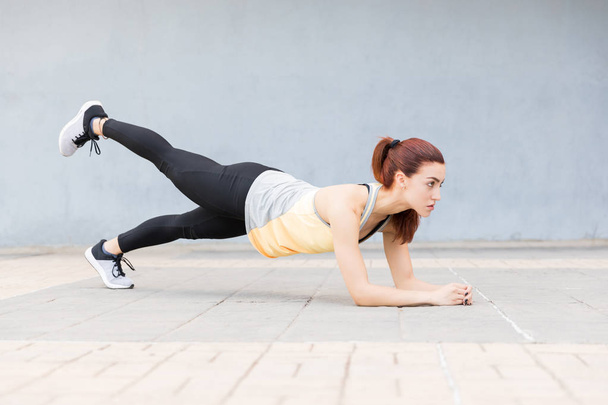 Full length of strong woman in plank position with leg up - Photo, Image