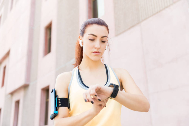 schöne Frau überprüft ihre Fitness-Fortschritte auf Smartwatch-App nach dem Training - Foto, Bild