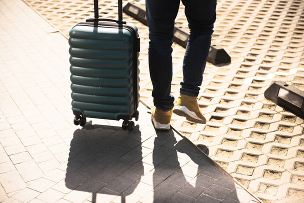 Man in the jeans walking with green electric suitcase on wheels on a street - Photo, Image