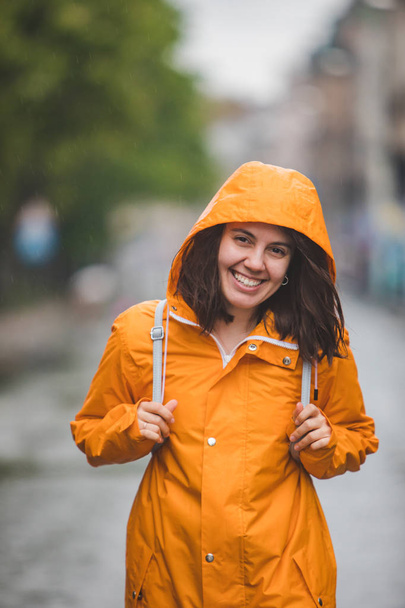junge hübsche lächelnde Frau im Regenmantel mit Kapuze - Foto, Bild