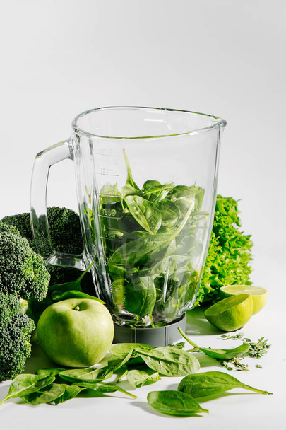 Ingrediënten voor groene smoothies in een blender. Gezond voedselconcept met spinazie en groene groenten. Vegetarisch voedsel. - Foto, afbeelding