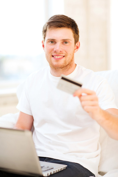 Man with laptop showing credit card at home - Photo, Image