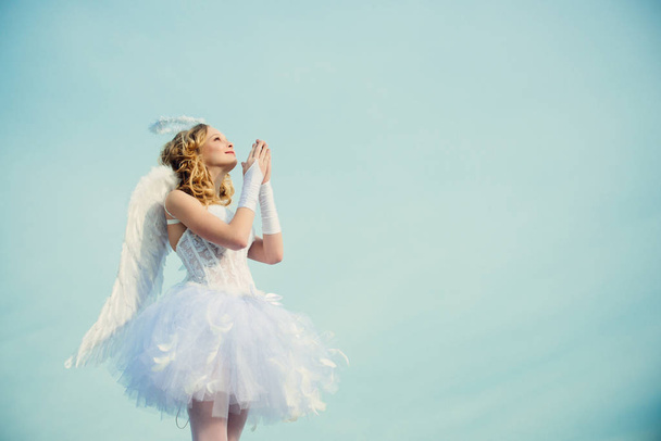 A beautiful teen with blonde curly hair as cupid - Valentines Day. Valentines day. Little angel in love. Girl angel with halo in white angel dress. - Foto, immagini
