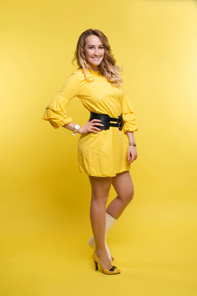 Cheerful beautiful woman in yellow dress having fun with plaster on her leg. - Фото, зображення
