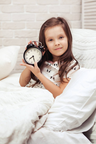 little child girl in pyjamas with clock - Foto, Imagem