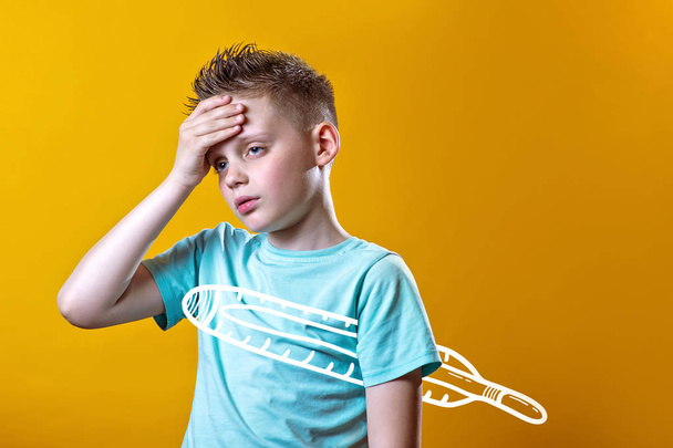 sick boy in light t-shirt measures the temperature of a thermometer on a colored background - Foto, immagini