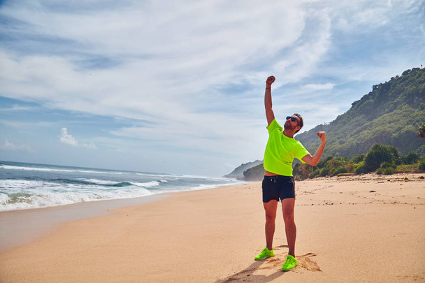 Человек празднует успех после хорошей тренировки / упражнений на песке
 - Фото, изображение