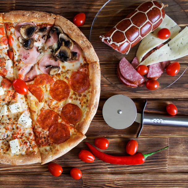 Una pizza de cuatro piezas con pepperoni, jamón, champiñones, salami, quesos
 - Foto, imagen