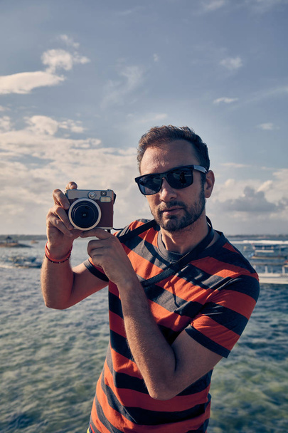 Man using vintage film camera on a ocean / sea vacation. - Fotoğraf, Görsel