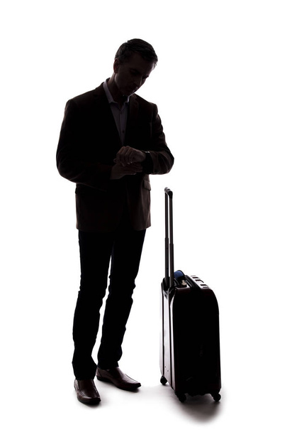 Silhouette of a traveling businessman going on a business trip.  He is waiting with luggage as if he is in the airport departure or arrival. Isolated on white background for composites.  - Фото, изображение