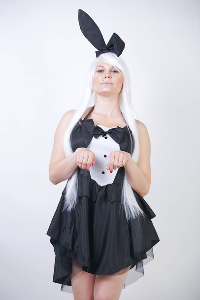 cute girl with long white hair with Bunny ears in rabbit costume on white background in Studio. a woman with a plus size body stands and do fashion poses in a black dress. - Photo, Image