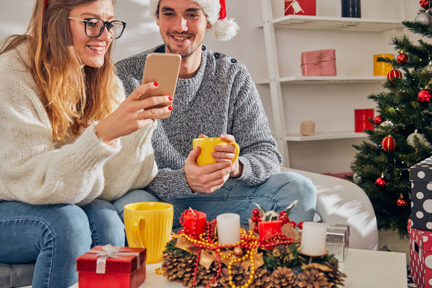 Joyeux couple profitant du Nouvel An / veille de Noël avec téléphone portable
  - Photo, image