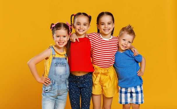 group of cheerful happy children on colored yellow backgroun - Фото, изображение