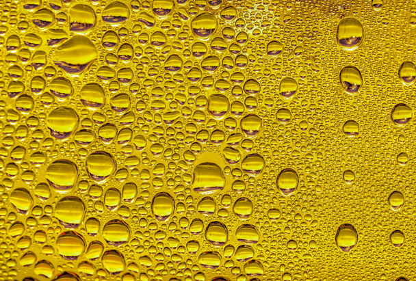 Gocce d'acqua sul vetro, birra di fondo gialla, sfondo nebbioso
. - Foto, immagini