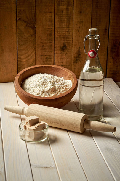 Ingredients for dough on pastry board with flour and rolling pin on table - Photo, Image