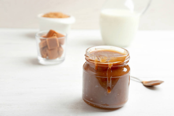 Jar of tasty caramel sauce on table, closeup. Space for text - Foto, immagini