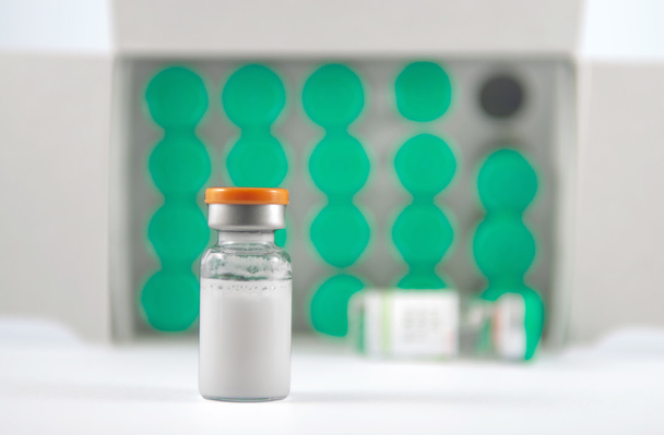 Frasco para injectáveis de tampa laranja sobre o fundo dos frascos verdes
 - Foto, Imagem