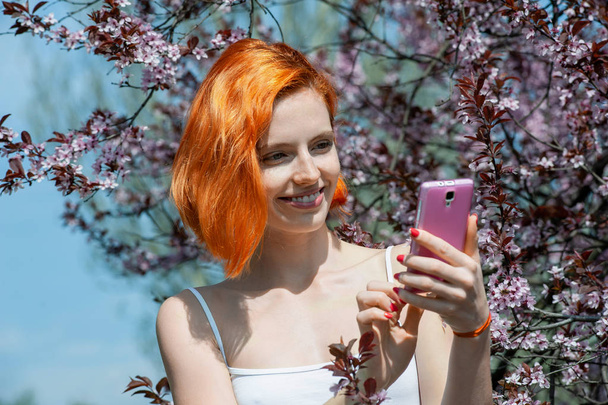 Attractive woman with fascinating smile holding her phone and lo - Fotografie, Obrázek