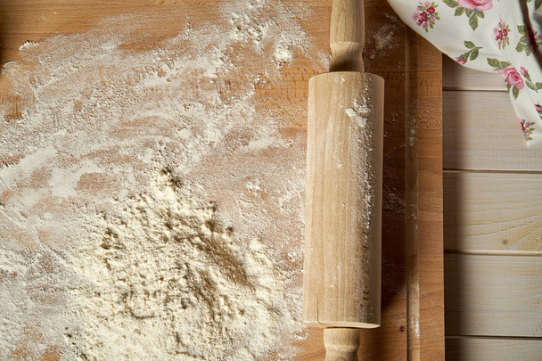 Rodillo sobre tabla pastelera espolvoreado con harina sobre mesa de madera
 - Foto, Imagen