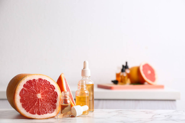 Bottles of essential oil and grapefruit slices on table. Space for text - Valokuva, kuva