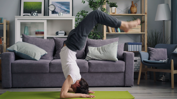 attrayant asiatique guy faire yoga asanas handstand et tête debout à la maison
 - Séquence, vidéo