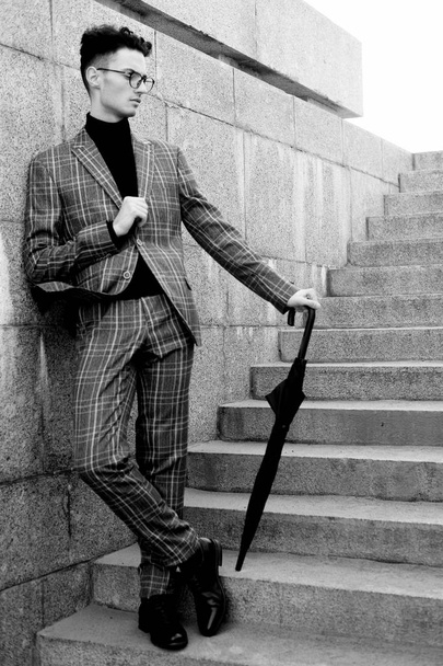 fashionable young man in glasses with umbrella standing on the stairs - Фото, зображення