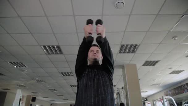 Adult man with overweight performs breeding with dumbbells. - Footage, Video