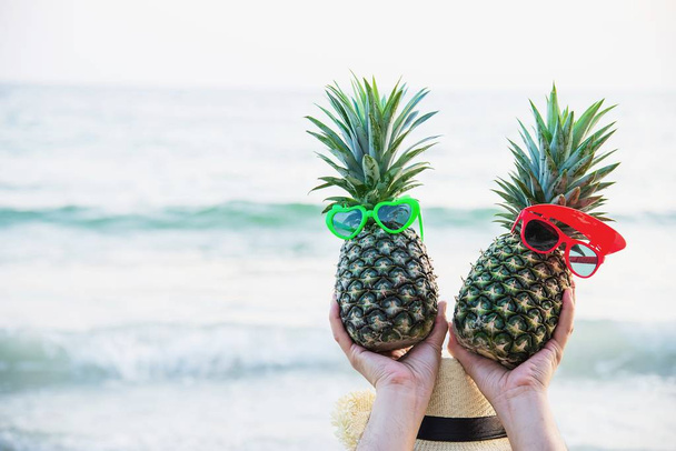 Lovely couple fresh pineapple putting boy and girl glasses in tourist hands with sea wave background - happy fun with healthy vacation concept - Foto, immagini