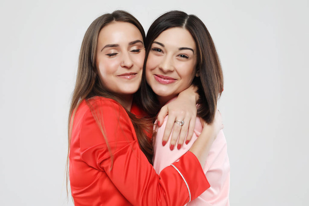 Lifestyle-, Freundschafts- und Personenkonzept - zwei schöne Mädchen im Schlafanzug, die sich umarmen und lächeln - Foto, Bild