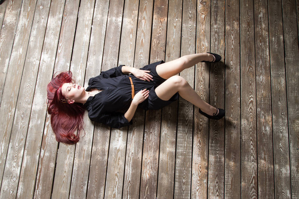 Młoda rudowłosa dziewczyna leżąca na podłodze. Widok z góry - Zdjęcie, obraz