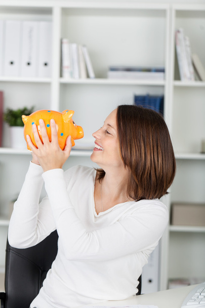 Businesswoman Holding Piggybank While Looking At It - Foto, Imagen