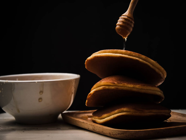 Pancake with honey syrup dipper and black background. - Fotoğraf, Görsel